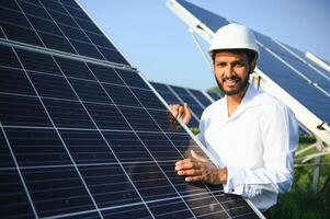 Portrait of Young indian male engineer standing near solar panels, with clear blue sky background, Renewable and clean energy. skill india, copy space. photo