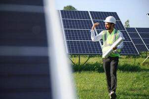 Portrait of Young indian male engineer standing near solar panels, with clear blue sky background, Renewable and clean energy. skill india, copy space. photo