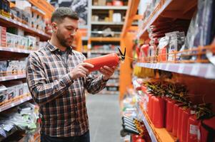 A man holds a fire extinguisher in his hand. A buyer in a hardware store selects a product photo