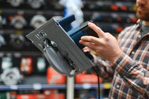 A man in a hardware store chooses a new orbital sander photo