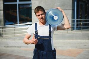 Smiling delivery man carrying water bottle on shoulder photo
