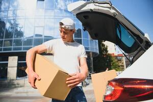 Smiling delivery man standing in front of his car photo