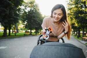 beautiful and young woman mother and baby in a stroller walking in the park photo