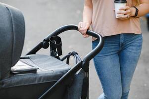 family, child and parenthood concept - happy mother walking with baby stroller in park. photo
