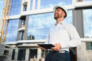 Construction engineer with the tablet pictures of objects on a construction site photo