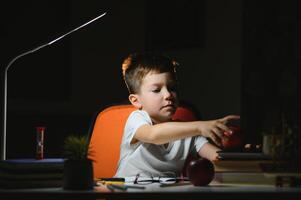 Boy learn lessons in the home setting at the table in the light of a table lamp. photo