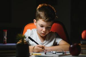 Boy learn lessons in the home setting at the table in the light of a table lamp. photo