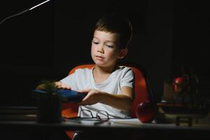 Boy learn lessons in the home setting at the table in the light of a table lamp. photo