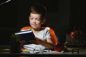 Boy learn lessons in the home setting at the table in the light of a table lamp. photo