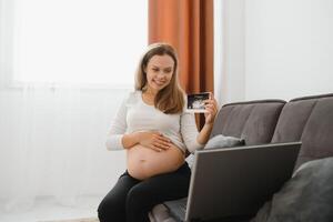 selective focus of cheerful pregnant woman showing ultrasound photos while having call