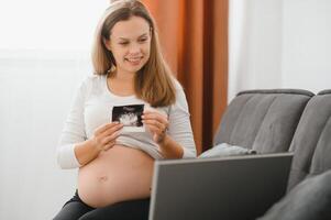 selective focus of happy pregnant woman showing ultrasound photos while having call