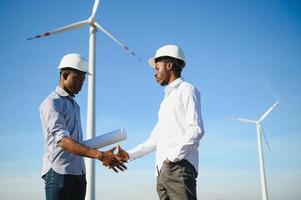 Young maintenance engineer team working in wind turbine farm at sunset stock photo