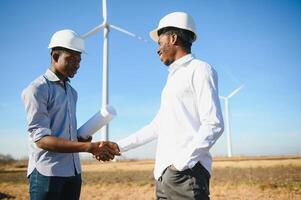 Young maintenance engineer team working in wind turbine farm at sunset stock photo