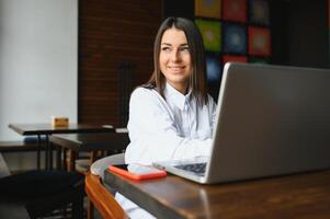 Beautiful Caucasian woman dreaming about something while sitting with portable net-book in modern cafe bar, young charming female freelancer thinking about new ideas during work on laptop computer photo