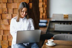 Young woman successful manager is talking via mobile phone with possible financial company employee and reading their resume on portable laptop computer during remote interview in co-working space photo