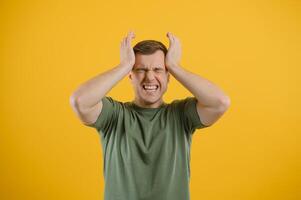 Portrait of a young man holding his head with his hands. Concept of despair and hopelessness. Frustration. Migraine photo
