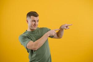 Wow, look at ads here Portrait of surprised shocked man pointing aside, showing blank copy space for idea presentation, commercial text. indoor studio shot isolated on yellow background. photo