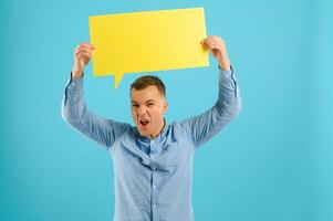 Happy smiling man holding yellow bubble speech, looking at camera over red background photo