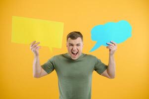 Cheerful young male pointing up and holding empty speech bubble with blank space for quote against vivid yellow background photo