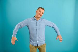Happy smiling handsome man in clothing, showing copy space, visual imaginary or something, or pressing virtual button, aqua marine blue color background. photo