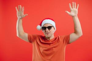 concept people, body language, approval, recommendationan excited man Santa Claus hat isolated on red studio background with space for text photo