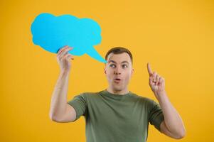 Young caucasian man isolated on yellow background holding a thinking speech bubble and doing OK sign photo