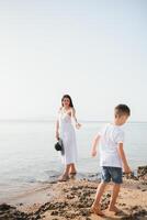 Happy mother and son walk along the ocean beach having great family time on vacation on Pandawa Beach, Bali. Paradise, travel, vacation concept photo