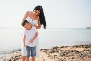 Happy mother and son walk along the ocean beach having great family time on vacation on Pandawa Beach, Bali. Paradise, travel, vacation concept photo