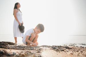 Mother and son playing on the beach at the day time. Concept of friendly family. photo