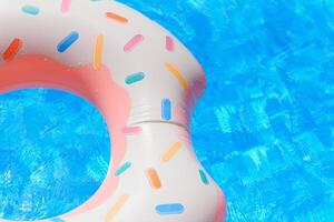 Hipster sprinkled donut float in sunny pool background straight down on bright clear pool water photo