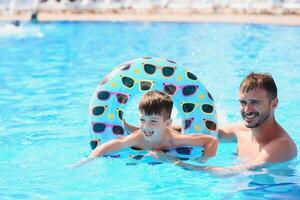 Father teaching his little son to swim in swimming pool. Vacation concept. photo