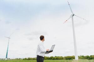 Engineer worker with laptop or computer at wind turbine power station construction site,copy space. photo