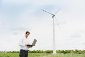 Engineer worker with laptop or computer at wind turbine power station construction site,copy space. photo