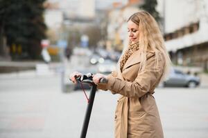 young woman on electro scooter in city. woman riding scooter in sunset light in street photo