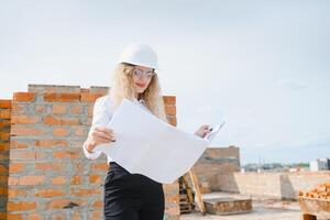 beatiful woman engineer is reviewing the plans of a construction work photo