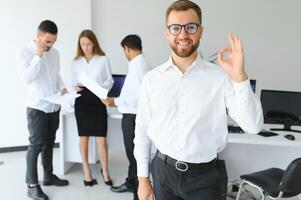 Team leader stands with coworkers in background photo