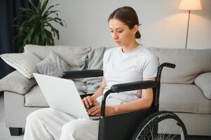 Female freelance programmer sitting in wheelchair and using computers while coding web game at home. photo