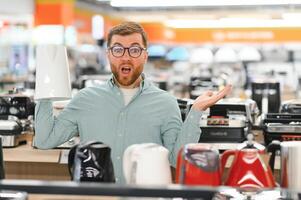 Man choosing electric kettle at store photo