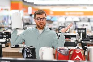 Man choosing electric kettle at store photo