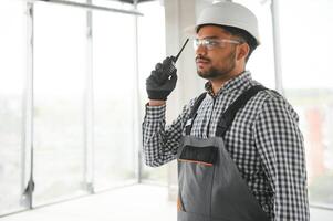 Young mixed race supervisor instructing workers using walkie-talkie at construction site. photo