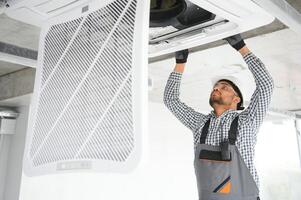 Professional technician maintaining modern air conditioner indoors. Space for text photo