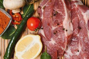 raw meat with fresh vegetables and spices on wooden background. Top view. Free space for text. prepare yourself concept. photo