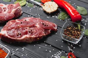 Raw pork meat with spices and vegetables on wooden table. photo