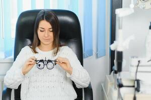 Selection of glasses for sight for the woman. The correct selection of points. Optical Salon. Optician. Trial lenses photo