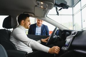 Nice business talk. Handsome young businessman talking on his smart phone and smiling while sitting on the front seat photo
