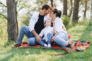 happy young family spending time outdoor on a summer day have fun at beautiful park in nature while sitting on the green grass. Happy family. photo