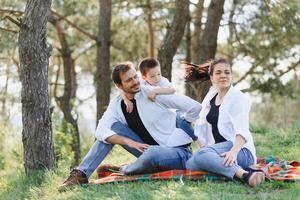 happy young family spending time outdoor on a summer day have fun at beautiful park in nature while sitting on the green grass. Happy family. photo