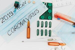 Surgical mask protective mask with CORONAVIRUS text. Virus 2019-n CoV in Wuhan, China. Tablets, mask, syringe photo
