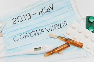 Surgical mask protective mask with CORONAVIRUS text. Virus 2019-n CoV in Wuhan, China. Tablets, mask, syringe photo