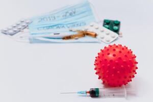 a test tube with a positive test for the CAVID-2019 coronavirus. medical devices on a white table. thermometer, phonendoscope, tablets, surgical masks photo